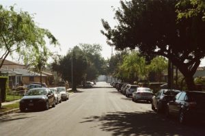 A street lined with cars and tress.