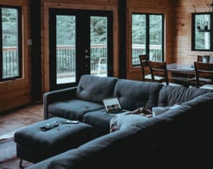 A patio door in a dark living room the leads two a wood deck.