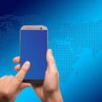 A hand holding a smart phone while the other hand uses a finger to scroll on the phone screen.