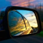 A car sideview mirror reflecting a sunset.