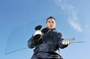 A man holding a glass windshield with the help of suction cup tool.