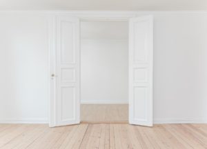 Two white doors open leading into an empty room
