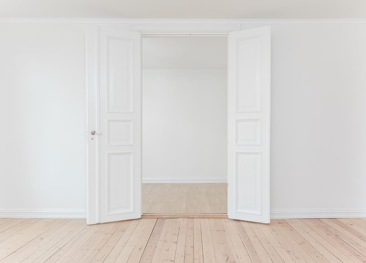 Two white doors open leading into an empty room