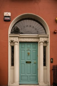 A teal colored door on a red building