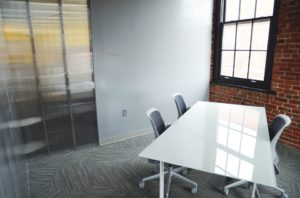 A small office with a white table and a glass window on a brick wall