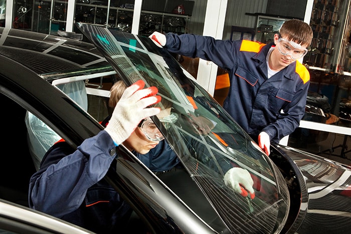 Two mechanics installing a new windshield.