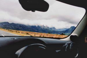A windshield view out to a cloud covered mountain range.