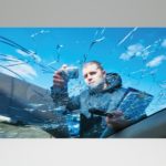 A man inspecting a cracked windshield.