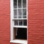 An exterior view of a single hung window on a red brick home.