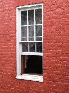 An exterior view of a single hung window on a red brick home.