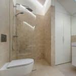 A clean, simple bathroom. In the bathroom with a glass door shower, a white toilet, and a white vanity.