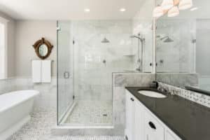 A glass shower with marble tiled walls.