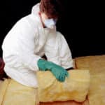 Worker laying fiberglass insulation.