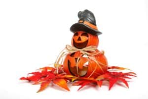 A ceramic pumpkin decoration. A large pumpkin with a large mouth. On top of the large pumpkin is a smaller one with a large smile and a witches hat.