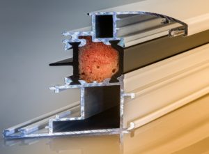 Orange window insulation sits between two white pieces of metal.