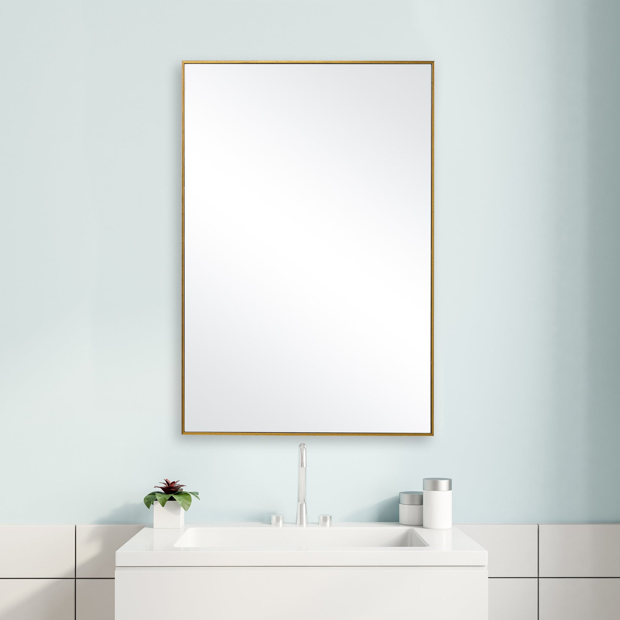 Woodbury Gold Mirror hanging above a white bathroom sink on a light blue wall